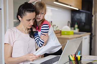 Image of a mother and her daughter looking at paperwork in front of a laptop