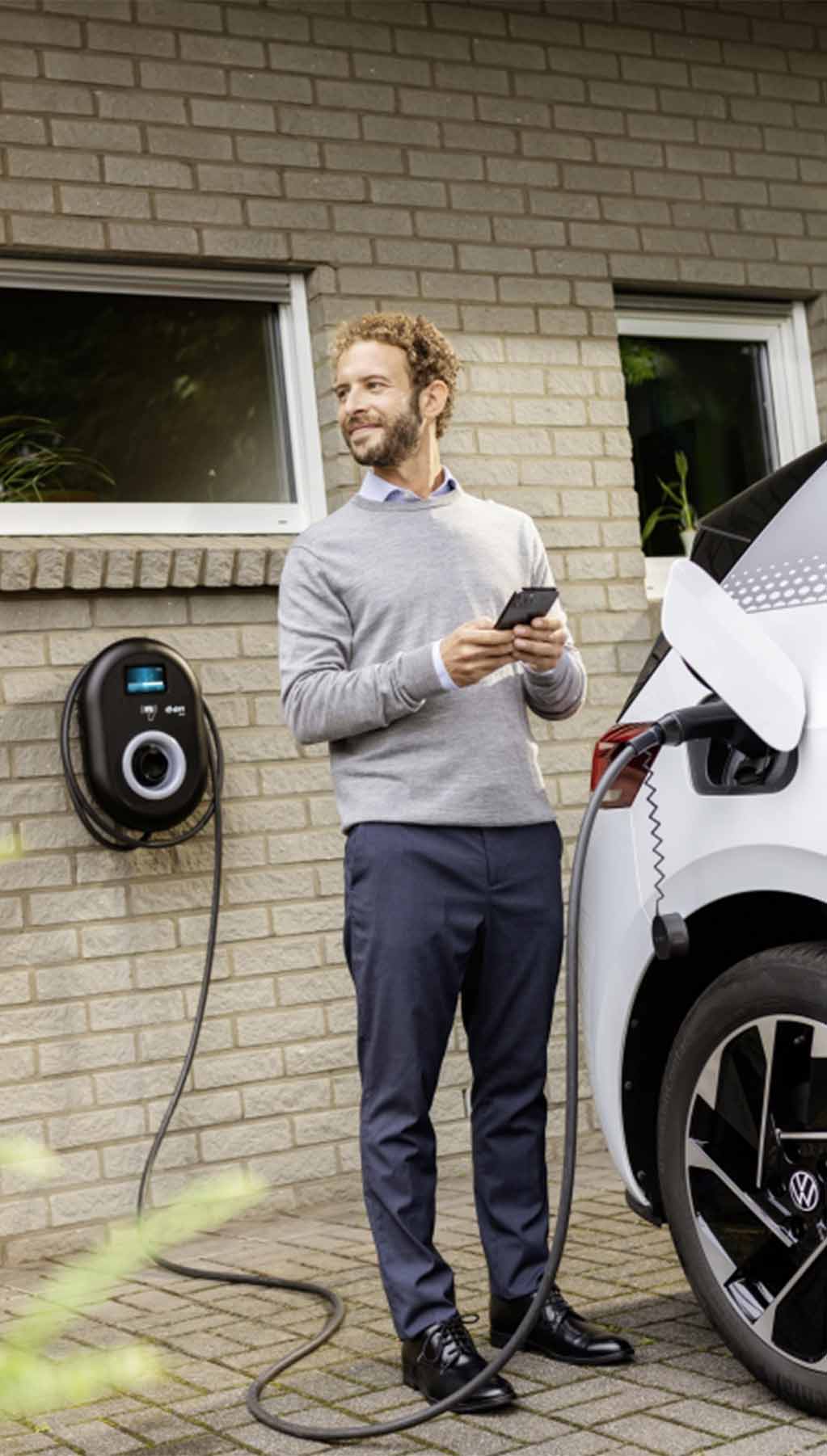 Man charging electric vehicle at home 