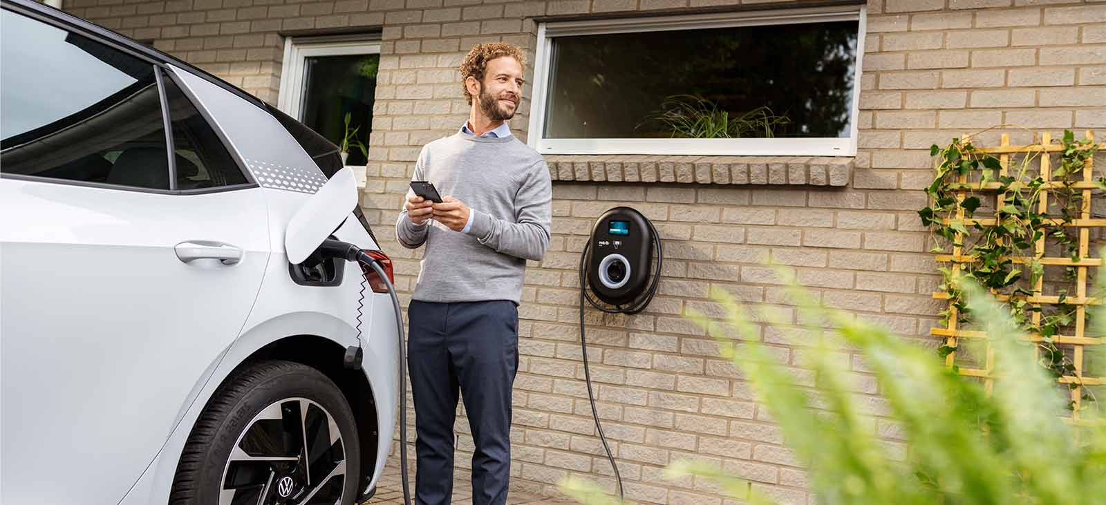Man charging electric vehicle at home 