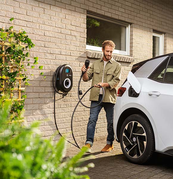 man charging electric car with home charger