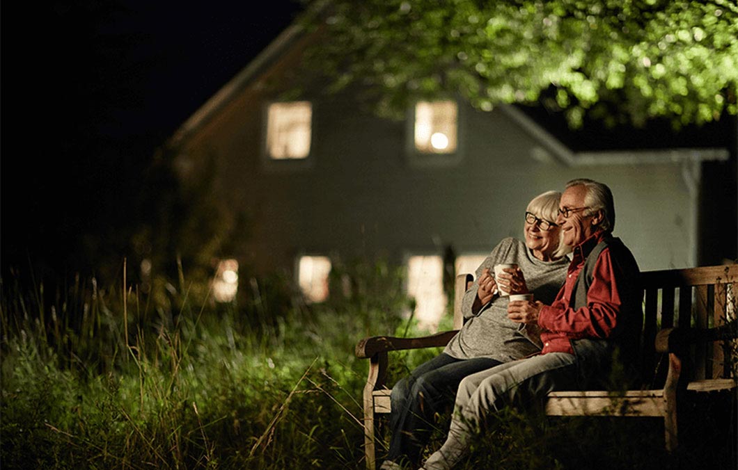 older couple hugging on a bench at night enjoying a drink together
