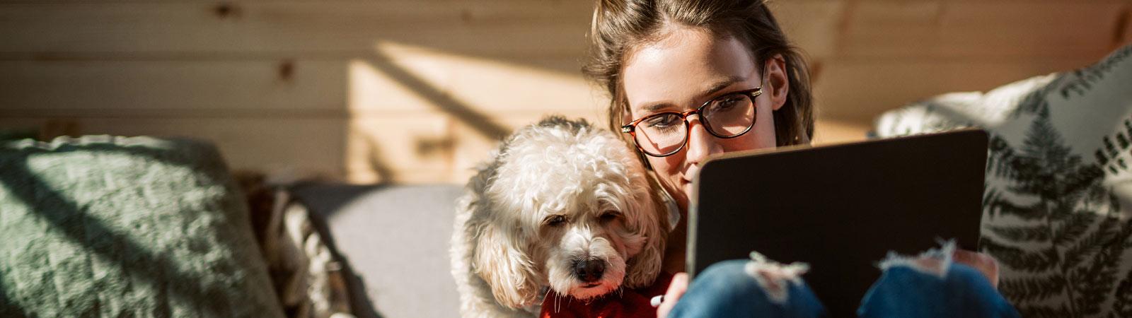 Image of a woman with her dog looking at a tablet
