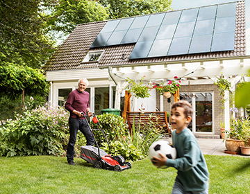 Grandad and grandson in garden solar panels on roof of house