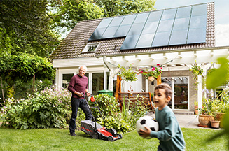 Grandad and grandson in garden solar panels on roof of house