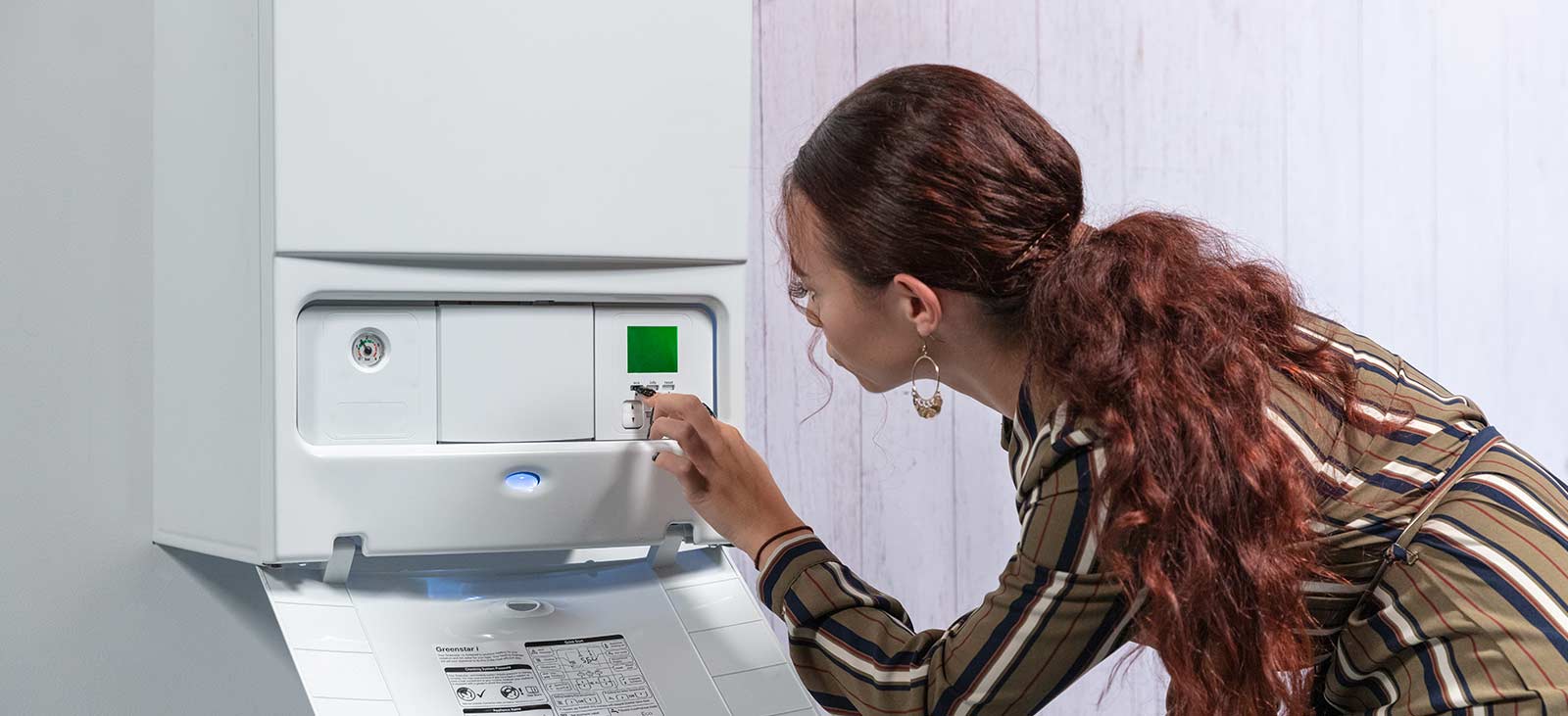 Image of a woman adjusting the settings on her boiler