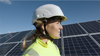 Image of engineer wearing a hard hat next to solar panels