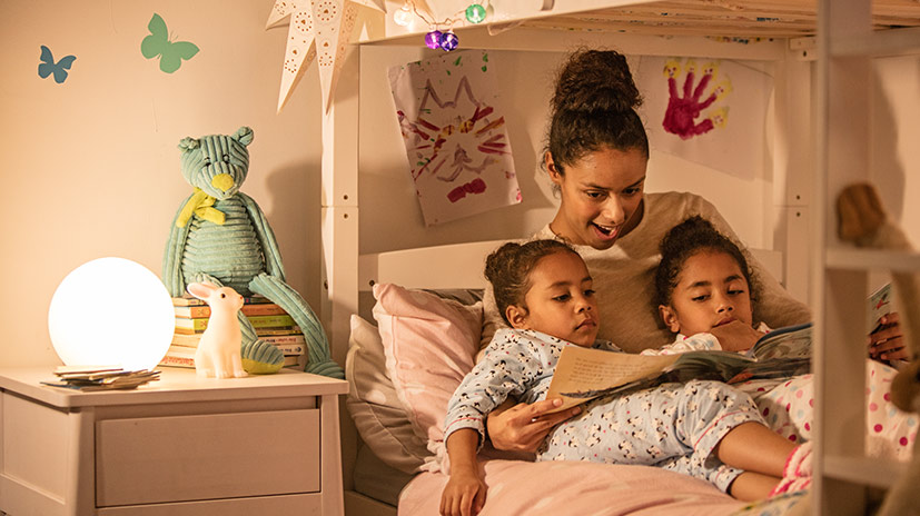 image of a mother reading to her two daughters in bed
