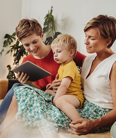 Image of a family sitting on their sofa looking at a tablet