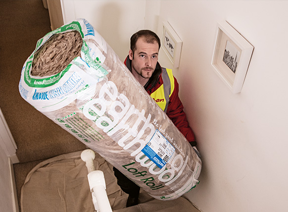 Image of an E.ON engineer with a roll of loft insulation