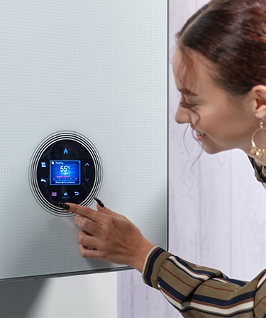 Image of a woman changing the thermostat on her boiler